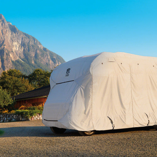 Car covered with a white protective cover in front of a mountainous landscape