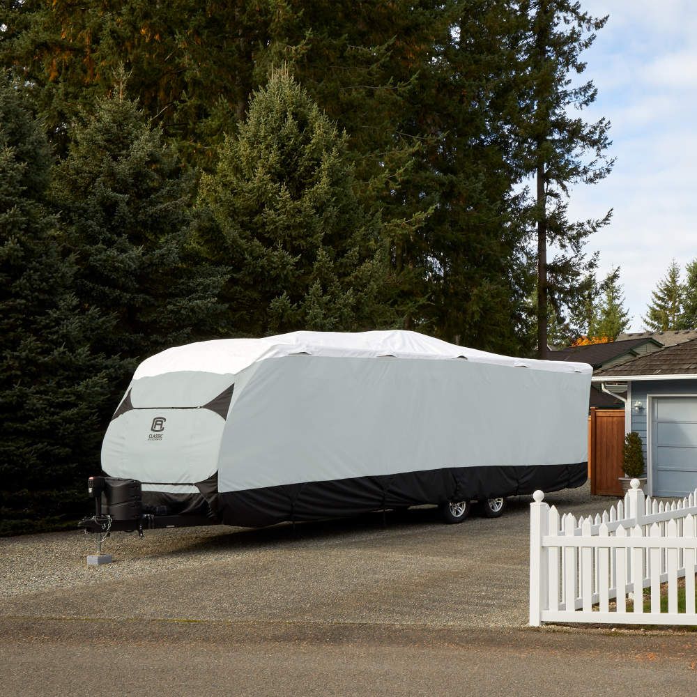 Classic Accessories outdoor camper trailer in front of a home with a white picket fence